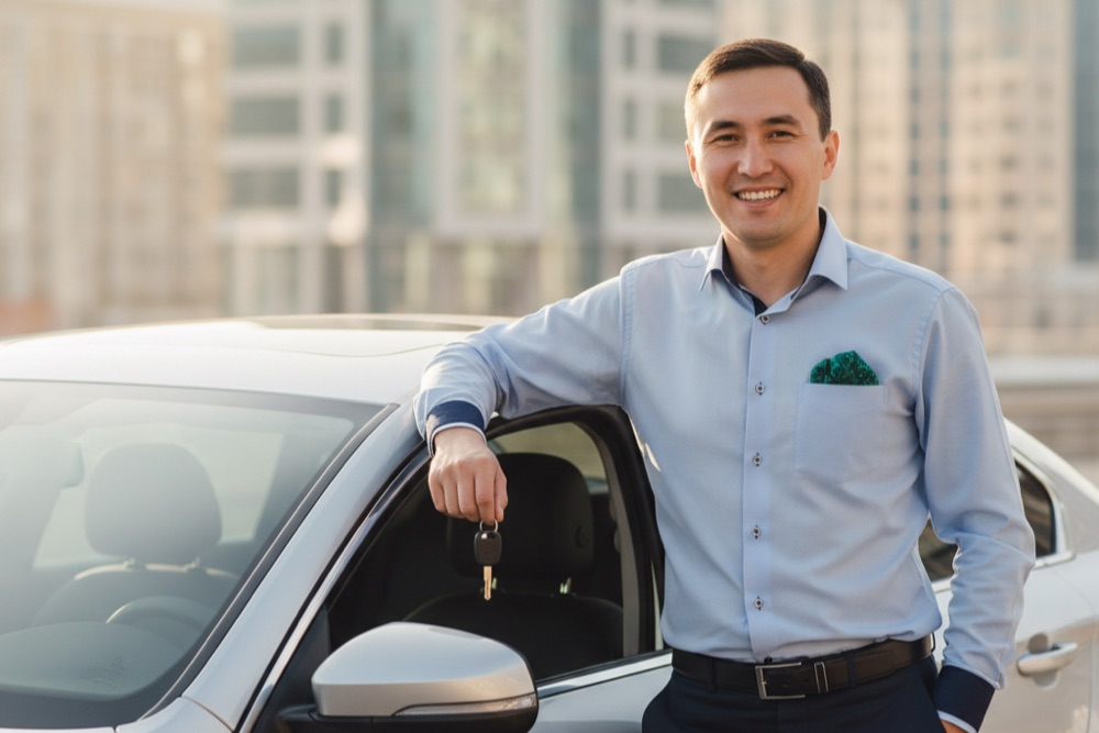 Довольный мужчина с ключами у автомобиля — заём под залог авто
